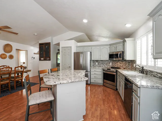 Kitchen featuring wood-finish flooring, light-toned cabinetry, stainless steel appliances, and stone countertops