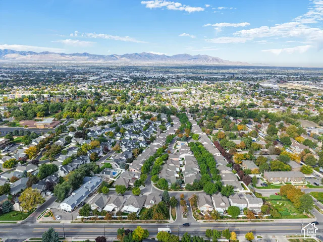 Expansive aerial perspective showcasing a residential development with mature trees, established landscaping, and distant mountains