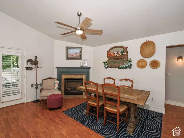 Vaulted ceiling with a ceiling fan, fireplace with a mantel and tile surround, French door with louvered blinds, and wood-finish flooring