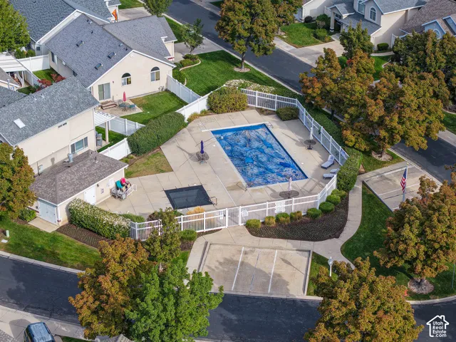 Community pool with surrounding concrete patio, white fencing, and integrated landscaping