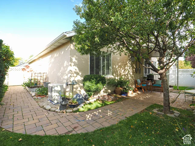 Exterior stucco finish with a mature shade tree, paver pathways, and established landscaping