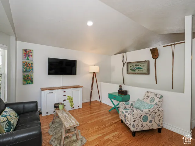 Wood-finish flooring, white built-in cabinetry with wood countertop, recessed lighting, and an angled ceiling
