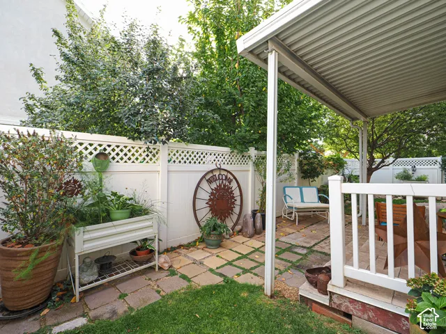 Patio with a slatted overhead cover, white railing, and decorative lattice fencing