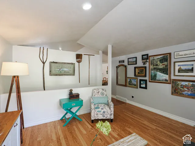 Hardwood flooring, crisp white trim, recessed ceiling lighting, and a vaulted ceiling