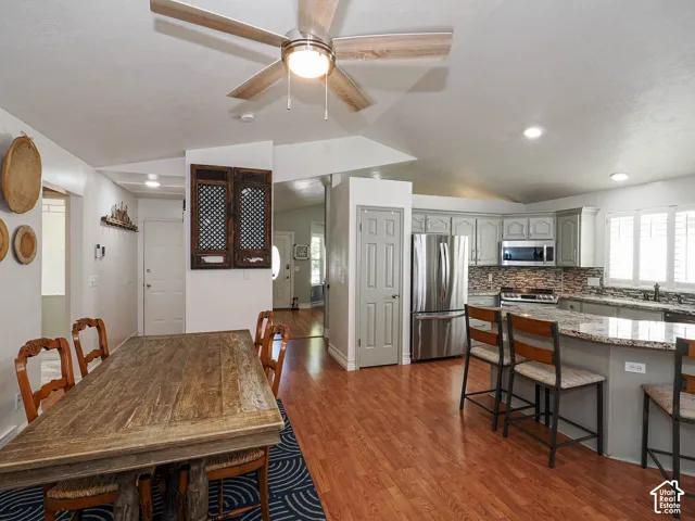 Open-concept living area featuring wood-finish flooring, a ceiling fan, recessed lighting, and a kitchen with stainless steel appliances