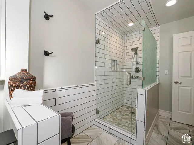 Shower with clear glass enclosure and subway tile surround, mosaic tile shower floor, and a built-in shower niche