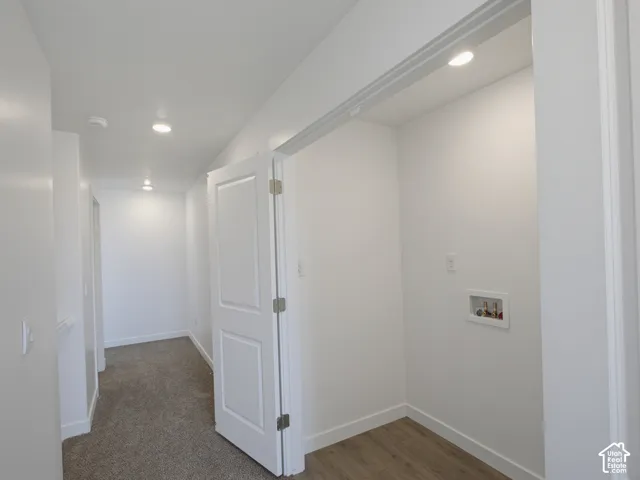 Laundry area with wood-finish flooring, recessed lighting, and bright white walls