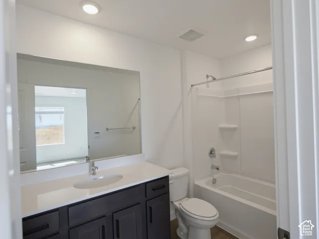Bathroom featuring a single vanity with dark cabinetry, integrated sink, and a large wall-mounted mirror
