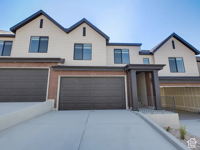 Contemporary townhome exterior featuring light-colored siding and brick accents