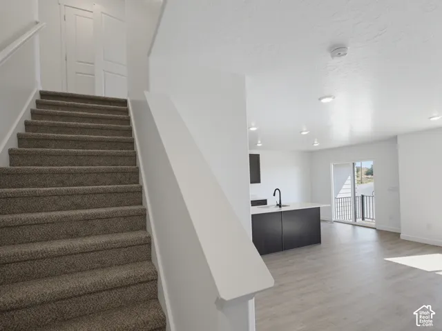 Open-concept living area featuring a modern kitchen island with a matte black faucet, recessed lighting, and wood-finish flooring
