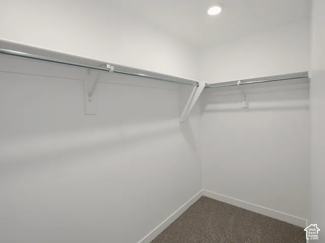 Walk-in closet featuring white walls, L-shaped shelving, and a recessed ceiling light