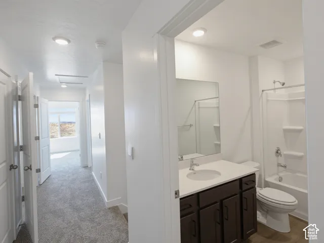 Bathroom featuring a dark wood-finish vanity with a single basin sink, white countertop, and a shower-over-tub combination