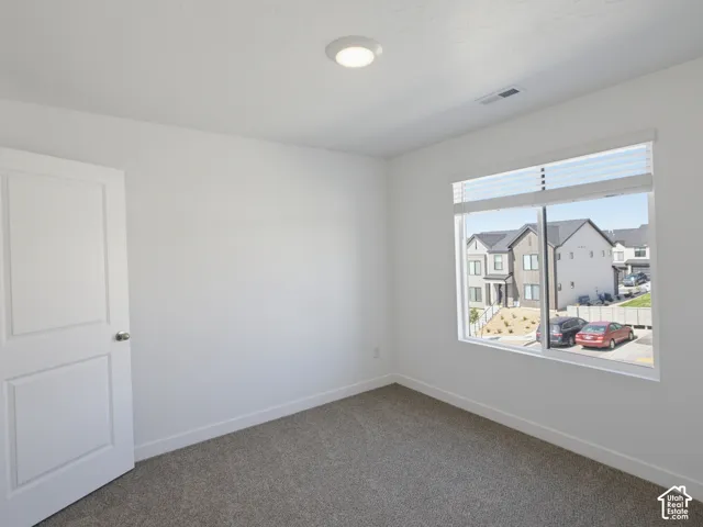 Recessed ceiling light, neutral wall paint, carpeted flooring, large window with blinds, and paneled interior door