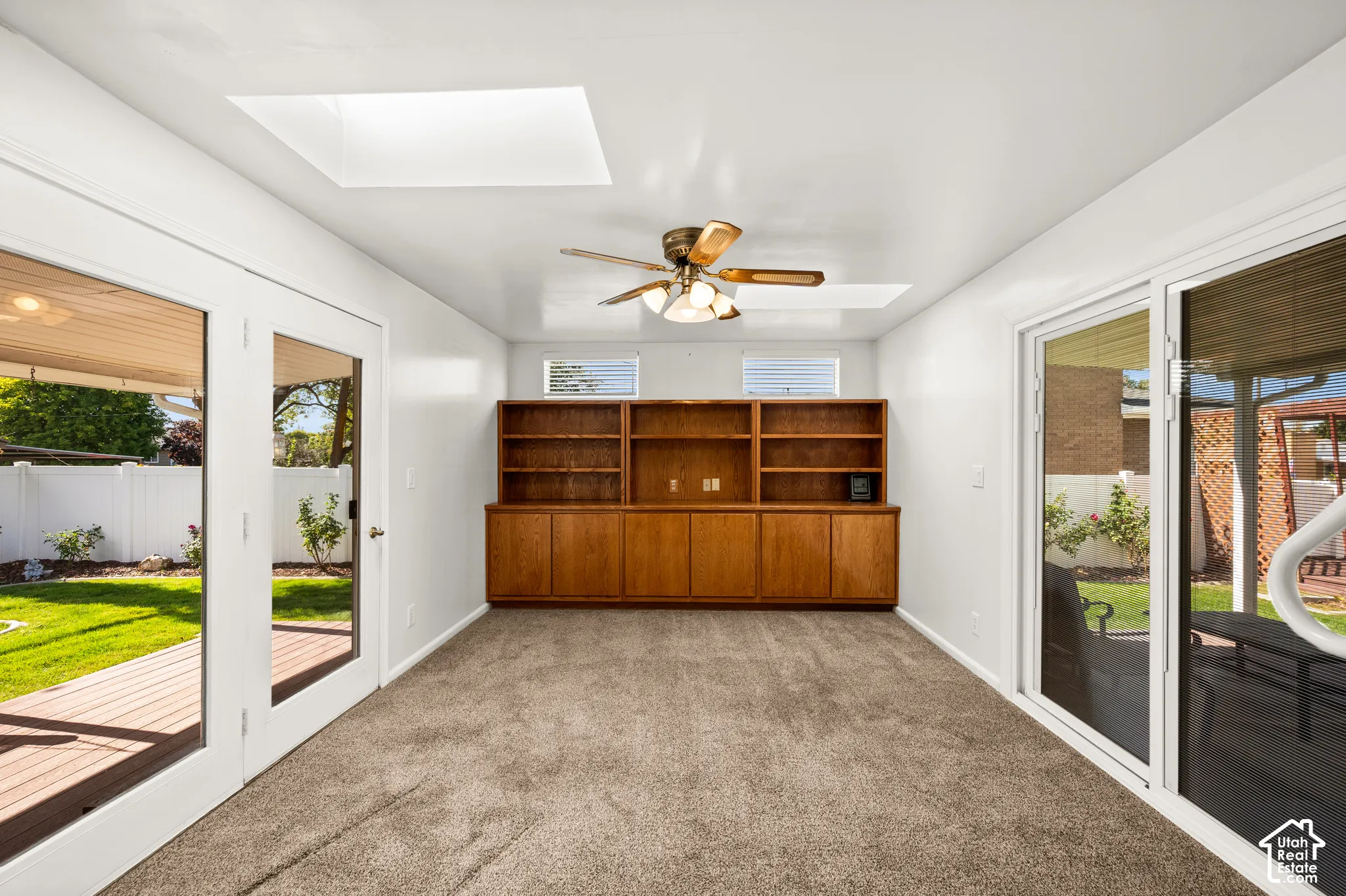 Built-in wood cabinetry with integrated shelving, two skylights, a ceiling fan, and sliding glass doors