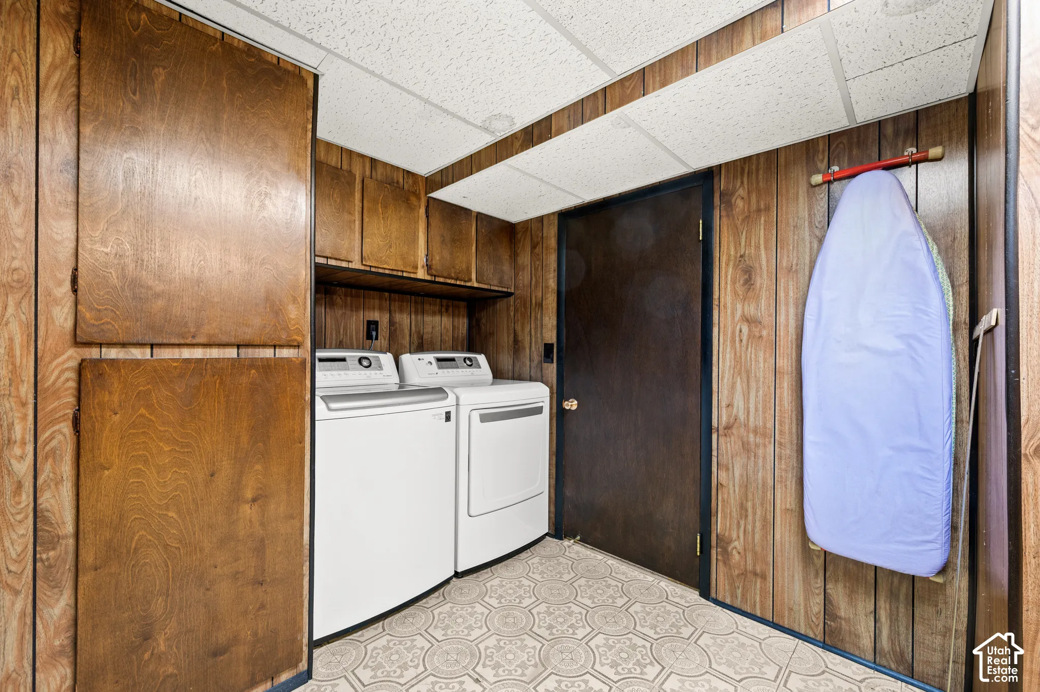 Washer and dryer appliances, wood-finish wall paneling, built-in cabinetry, and patterned flooring