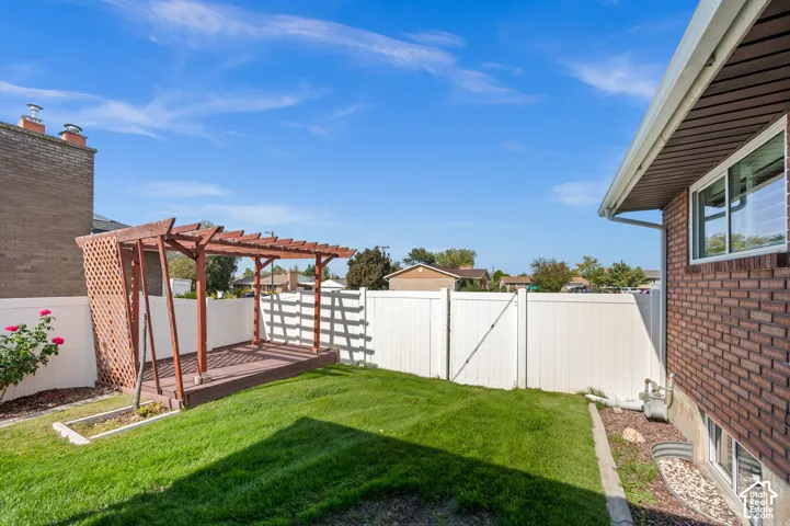 Manicured lawn with a wood pergola and a white privacy fence