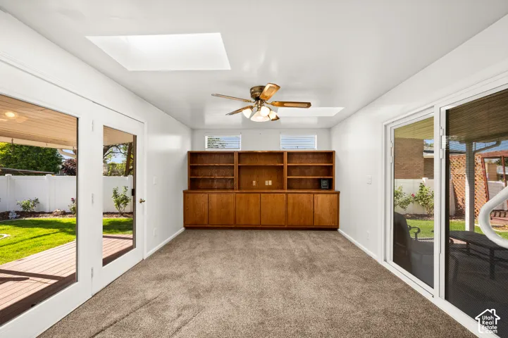 Built-in wood cabinetry with integrated shelving, two skylights, a ceiling fan, and sliding glass doors