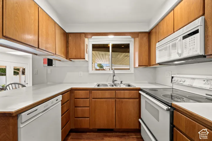 Wood cabinetry, white countertops, stainless steel sink, built-in microwave, and electric range