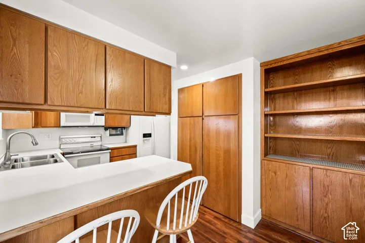 Kitchen featuring wood cabinetry, white countertops, built-in shelving, a double basin sink, and a full-size refrigerator