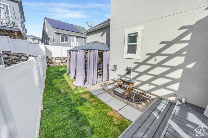 Manicured lawn, white vinyl fencing, rock retaining wall, built-in window well, and side yard access