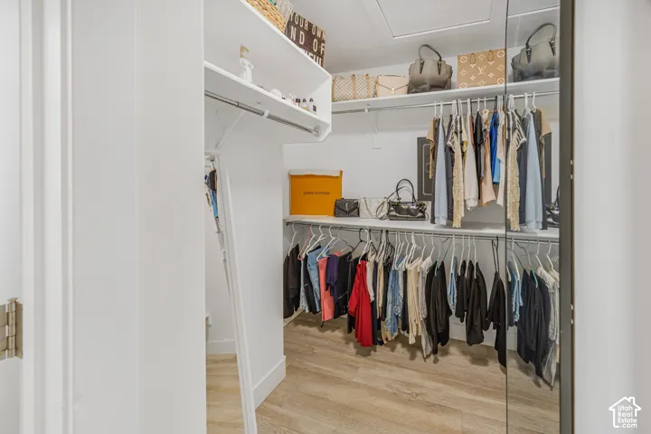 Custom closet system featuring built-in shelving, multiple hanging rods, and wood-finish flooring