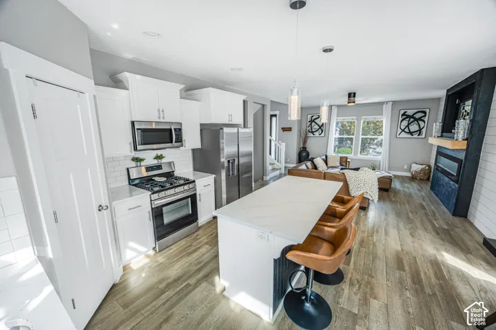 Gourmet kitchen with white cabinetry, stainless steel appliances, and a central island