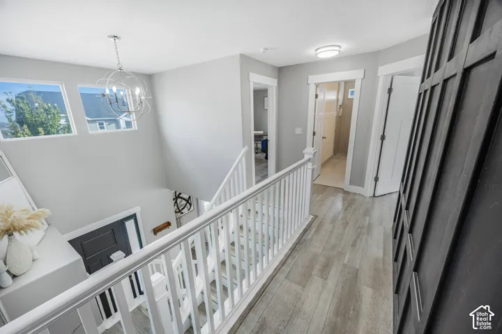 Staircase featuring white balusters and handrails, wood-finish flooring, a contemporary chandelier, recessed lighting, and upper-level windows