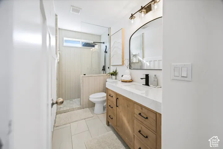 Walk-in shower with clear glass enclosure, natural wood-finish vanity with countertop, and modern black fixtures