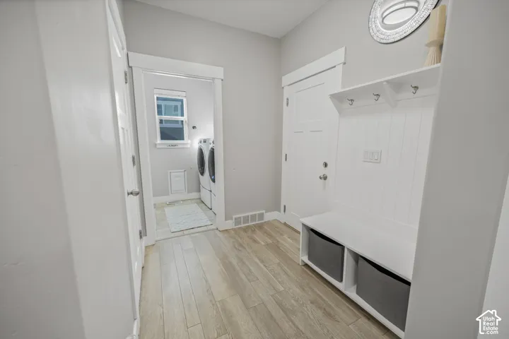 Built-in hall tree with storage, wood-finish flooring, white paneled doors, and a laundry area with a window