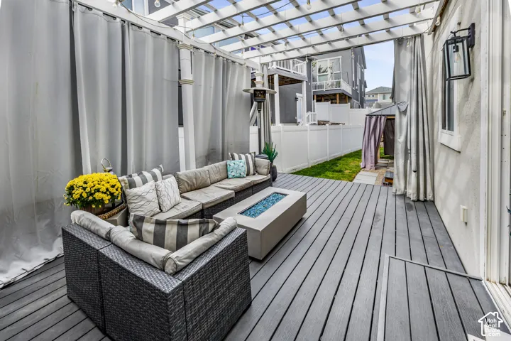 Expansive outdoor deck with a pergola, privacy curtains, built-in fire pit, and white privacy fencing