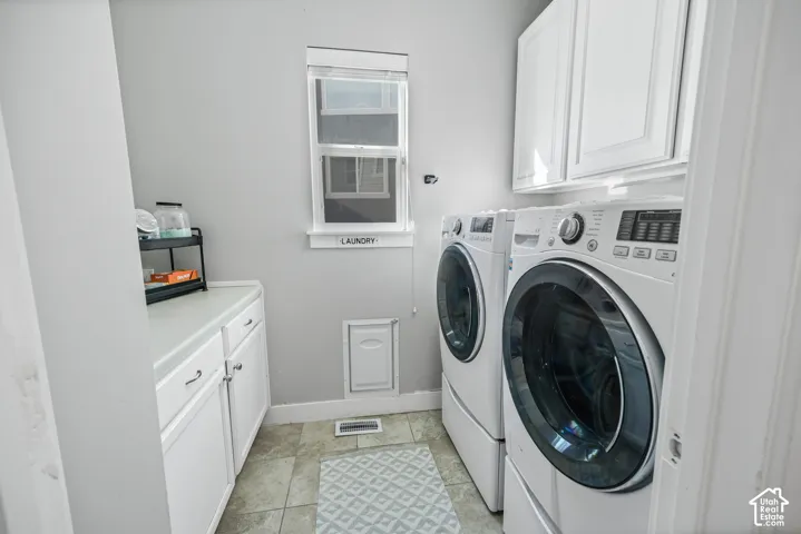 Dedicated laundry area featuring white cabinetry, a countertop surface, a single window, and tiled flooring