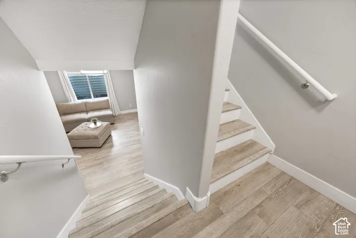 Light wood-finish flooring throughout, white stair risers, and white handrails