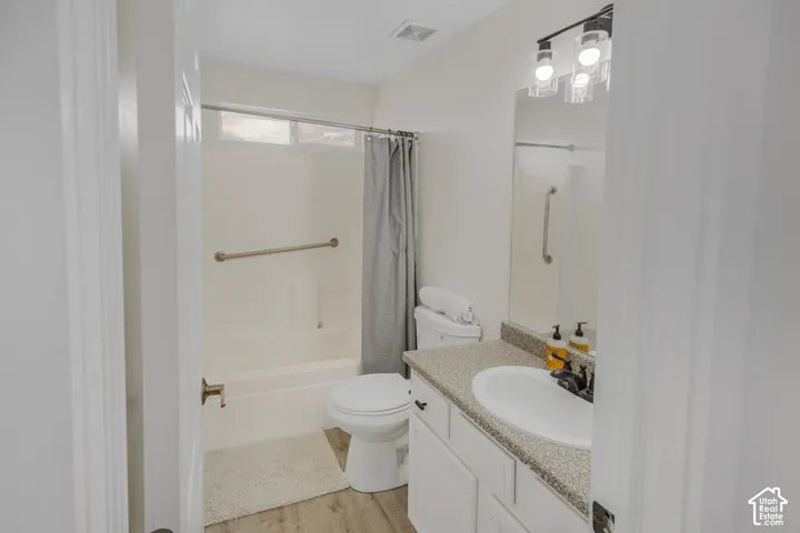 Bathroom featuring a vanity with an integrated sink, a speckled countertop, and wood-finish flooring