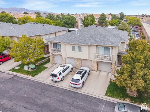 Multi-unit property featuring two-story construction with balconies, attached garages, and a paved driveway