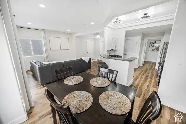 Open-concept living space featuring wood-finish flooring, recessed lighting, and a kitchen peninsula with a dark countertop and white cabinetry