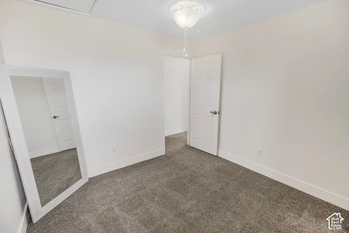 Neutral wall color, gray carpeting, white trim, white interior door, and a ceiling-mounted light fixture