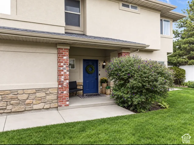 Stucco exterior with stone accents, brick columns, and a blue entry door