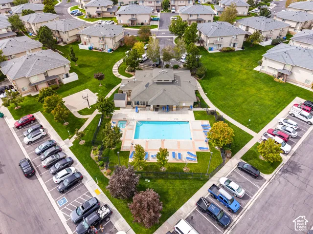 Centrally located community clubhouse featuring an outdoor swimming pool, separate spa, surrounding paved patio, and adjacent green space