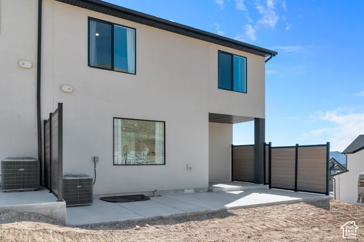 Exterior featuring a concrete patio, contemporary privacy fencing, and black-framed windows