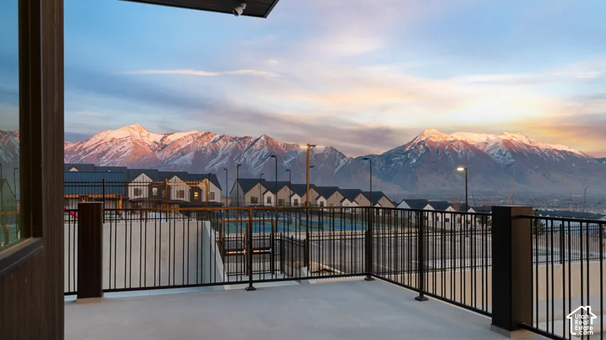 Expansive outdoor patio with metal railing and concrete flooring, offering mountain scenery