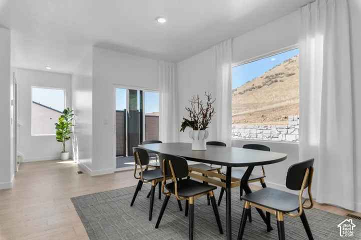 Recessed lighting, wood-finish flooring, sliding glass door, white walls, and a large window