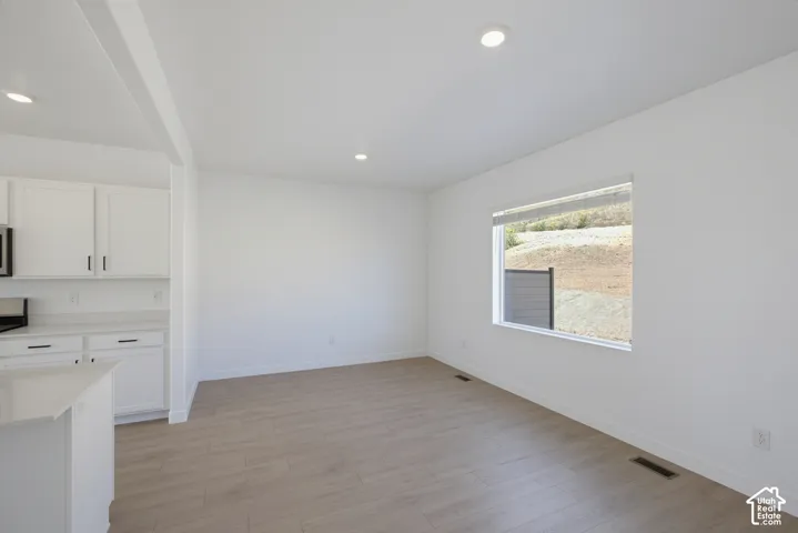 White cabinetry with black hardware, recessed ceiling lighting, light wood-finish flooring, and white walls