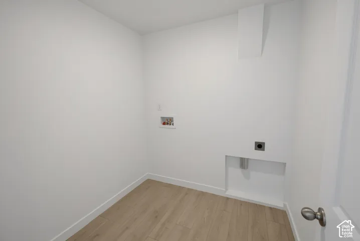 Dedicated laundry area featuring wood-finish flooring, white walls, and essential utility hookups