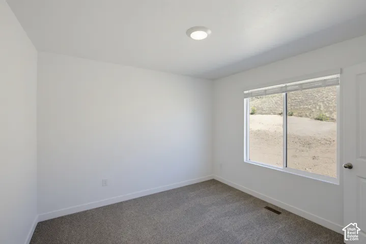 Bright secondary bedroom with large sliding glass door, carpet flooring, recessed ceiling lighting, and fresh white wall finishes