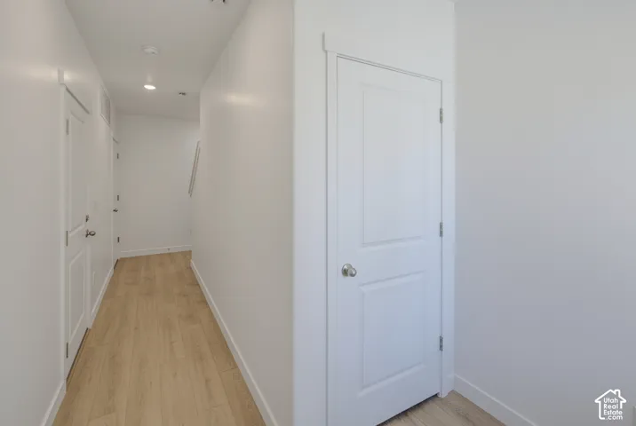 Wood-finish flooring with white trim, recessed lighting, and white paneled doors