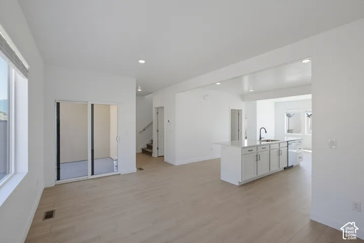 Open-concept living area with wood-finish flooring, recessed lighting, and large windows