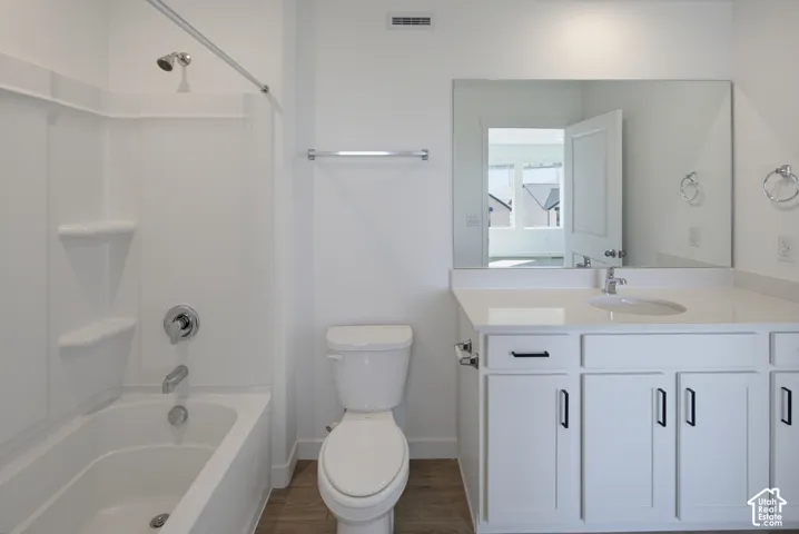 White vanity with an integrated sink and matte black hardware, large frameless mirror, white toilet, and a white tub with shower