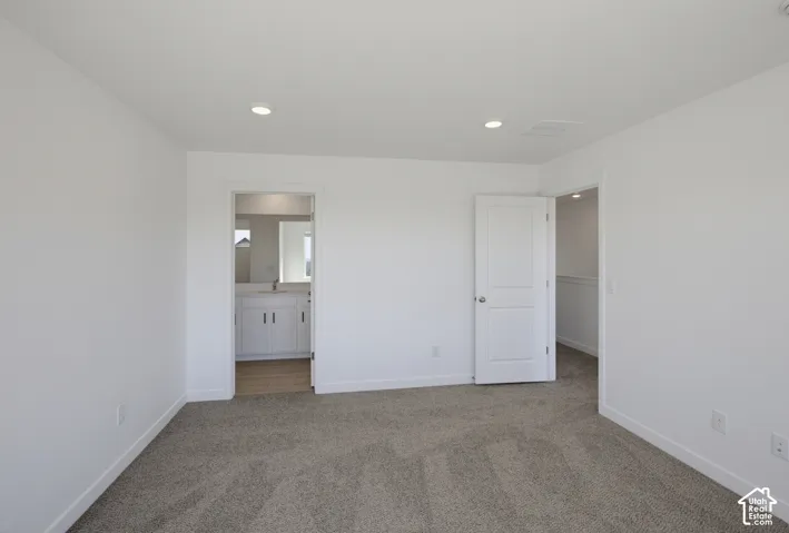 Recessed lighting, carpeted flooring, two-panel interior doors, and a bathroom featuring a white vanity with a mirror