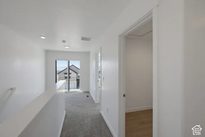 Recessed ceiling lighting, sliding glass door, carpet flooring, and white painted walls