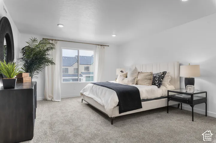 Recessed lighting, large window with blinds, carpeted flooring, and a paneled headboard